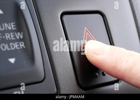 A woman's hand appuie sur le bouton d'urgence sur tableau de bord de voiture Banque D'Images