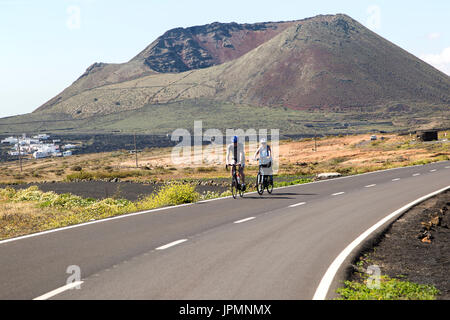 Les cyclistes sur route menant au cône du mont Corona volcano et Ye village, Haria, Lanzarote, îles Canaries, Espagne Banque D'Images