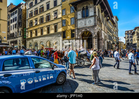 Une place près du Duomo à Florence Italie occupé par les touristes, une voiture de police et un cheval et un chariot avec une femme Italienne de la conduite sur une chaude journée d'été Banque D'Images