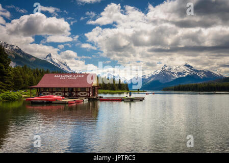 Boat House et des canoës sur une jetée au Lac Maligne dans le Parc National de Jasper, Canada, avec les cimes enneigées des Rocheuses canadiennes dans le backgroun Banque D'Images