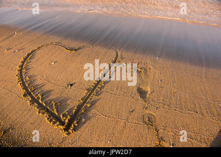 Coeur dessiné sur le sable. L'approche des vagues. Été plage vacances Banque D'Images