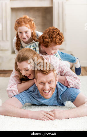 Belle famille rousse heureux de s'amuser ensemble sur les tapis, le grand portrait de famille Banque D'Images