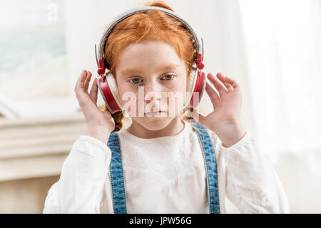 Portrait de petite fille à l'écoute de la musique dans le casque à la maison Banque D'Images