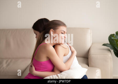 Deux jeunes femmes friends hugging on sofa Banque D'Images