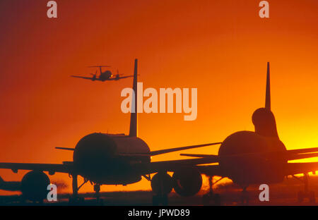 757 de Boeing et Lockheed L1011 Tristar queue sur la voie de circulation avec Embraer EMB-120 Brasilia s'envolent derrière au crépuscule Banque D'Images