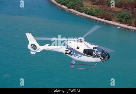 Eurocopter EC-120 Colibri en vol du prototype sur la route bleu turquoise de la mer avec la côte derrière Banque D'Images