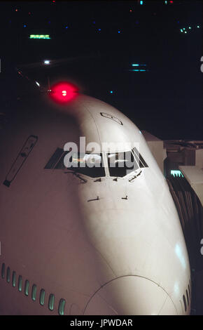 Nez et le pare-brise d'un Boeing 747-200 la nuit avec le feu rouge au-dessus de pont supérieur tout en clignotant stationné à la porte Banque D'Images