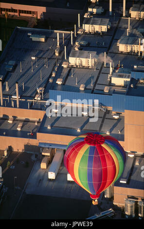 Montgolfières multicolores survolant une série de toits d'usine Banque D'Images