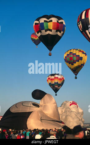 Foule de gens regardent comme Mickey Mouse en forme de ballon est spécial d'être gonflés à l'autre ballon escalade après décollage derrière Banque D'Images