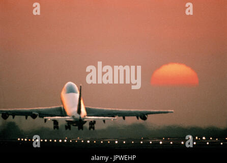 Boeing 747-200 le décollage au coucher du soleil avec la piste-phares sur Banque D'Images