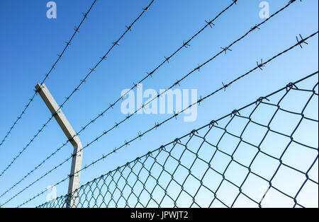 Barbelés enroulés avec ses griffes d'acier sur le dessus d'une clôture à mailles assurant la sécurité, empêchant l'accès ou l'évasion des prisonniers, Banque D'Images