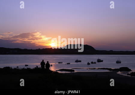 Couple regardant le coucher de soleil sur Iona de Fionnphort sur l'île de Mull, en Ecosse Banque D'Images
