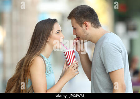 Portrait de vue de côté un couple heureux de partager un rafraîchissement à emporter dans la rue Banque D'Images