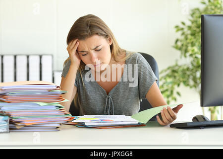 Vue avant, portrait d'un employé inquiet mauvaise lecture assise dans son rapport à l'office de bureau Banque D'Images