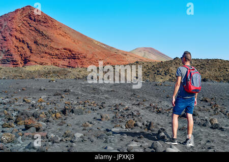 Un jeune homme de race blanche vue de derrière de transporter un sac à dos en randonnée dans un paysage volcanique Banque D'Images