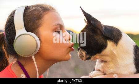 Girl kissing her dog - boston terrier - et d'écouter de la musique Banque D'Images