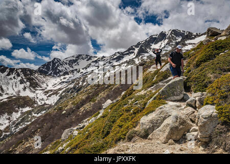 Les nuages au-dessus de Monte Renoso spectaculaire sommet, sur la droite, deux randonneurs sur le sentier GR 20 variante près de refuges de montagne Capannelle, Haute-Corse, Corse, France Banque D'Images