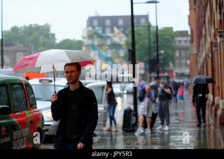 Les gens avec des parasols à l'extérieur de St Pancras Station & taxis en attente sur un jour de pluie à Londres, Angleterre Banque D'Images