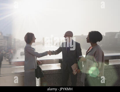 Poignée de gens d'affaires Silhouette urbaine ensoleillée sur pont sur la rivière Thames, London, UK Banque D'Images