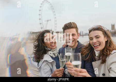 Portrait enthousiaste, smiling friends toasting champagne, près de roue du millénaire, London, UK Banque D'Images