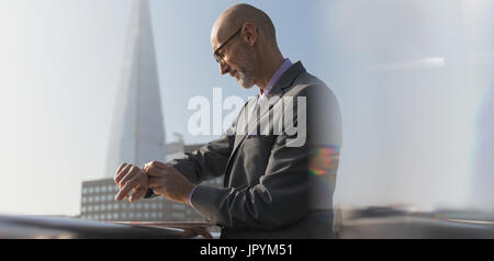 Businessman checking smart watch à l'extérieur, London, UK Banque D'Images