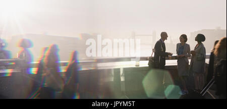 Silhouette business people talking on sunny urban bridge, London, UK Banque D'Images