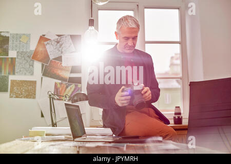 Photographe mâle en utilisant un appareil photo numérique de bureau ensoleillé Banque D'Images