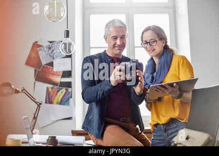 Photographers using digital tablet in office et d'un appareil photo numérique Banque D'Images