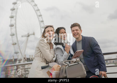 Portrait of laughing friends with digital tablet près de roue du millénaire, London, UK Banque D'Images