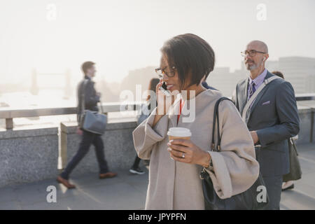 Silhouette businesswoman talking on cell phone et de boire du café sur urban bridge, London, UK Banque D'Images