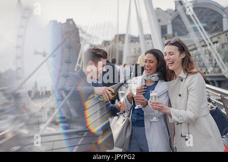 Amis souriant, heureux de célébrer, pouring champagne en ville, London, UK Banque D'Images