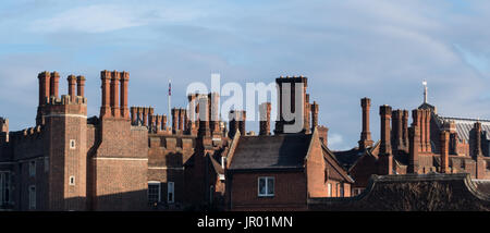 Détail de brique rouge période Tudor sur le toit du bâtiment avec les toits de cheminées et de parapets contre le ciel bleu Banque D'Images