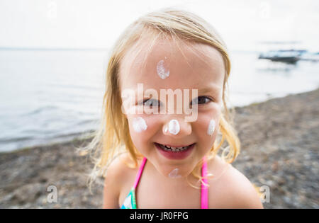 Une jeune fille de race blanche avec un écran solaire sur son visage pose pour une photo à Seneca Lake ; Dresde, New York, États-Unis d'Amérique Banque D'Images