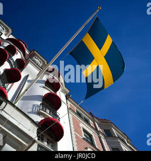 Low Angle View of the Swedish Flag et un bâtiment avec des auvents rouges sur les fenêtres, Ostermalm District ; Stockholm, Suède Banque D'Images