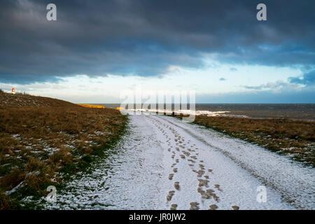 Des traces de pas dans la neige vers le bas un sentier menant à l'horizon ; à South Shields, Tyne and Wear, England Banque D'Images