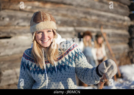 Portrait d'une jeune femme portant un chapeau et Sweater par une cabane en hiver ; Homer, Alaska, United States of America Banque D'Images