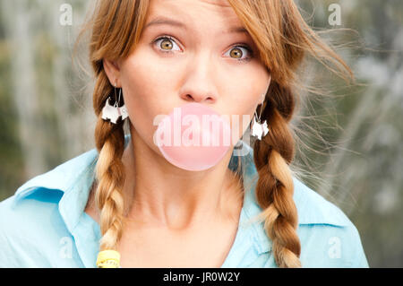 Beau jeune étudiant girl blowing bubble de chewing-gum et à la recherche dans l'appareil photo Banque D'Images