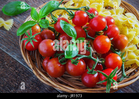 Produits frais bio tomates cerise et coller avec le basilic et l'ail sur fond sombre Banque D'Images