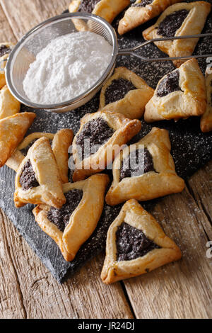 Les cookies ou oreilles Hamantaschen hamans juif traditionnel gros plan doux sur la table verticale. Banque D'Images