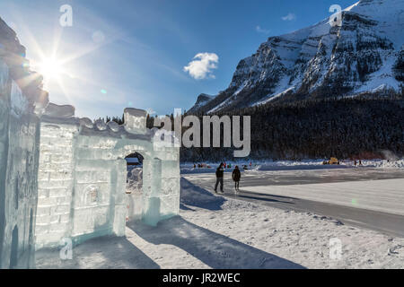 Le soleil brille derrière une glace château construit sur le lac Louise dans le parc national de Banff avec Patineurs Patinage sur le lac en arrière-plan Banque D'Images