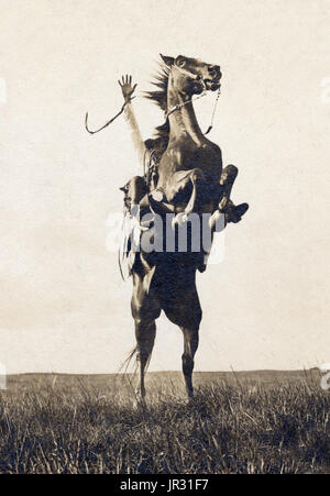 Bronco busting sur l'intervalle ouvert avec un bronco passant sur ses pattes arrière et le cavalier, Erwin E. Smith, soulevant sa main droite. Cow-boys de l'Ouest américain a développé une culture personnelle de leur propre, un mélange de frontière et les valeurs victoriennes que même des vestiges conservés de la chevalerie. Ces travaux dangereux dans des conditions d'isolement nourrit aussi une tradition d'autonomie et de l'individualisme, avec une grande valeur mis sur l'honnêteté, illustré par des chansons et de la poésie. Le cow-boy moyen gagné environ un dollar par jour, plus la nourriture, et, quand, près de la maison ranch, un lit dans le dortoir, habituellement une caserne-l Banque D'Images