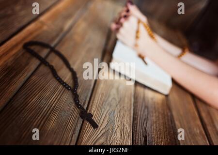 Jeune femme priant mains avec du chapelet et la Sainte Bible. Concept de la Religion Banque D'Images