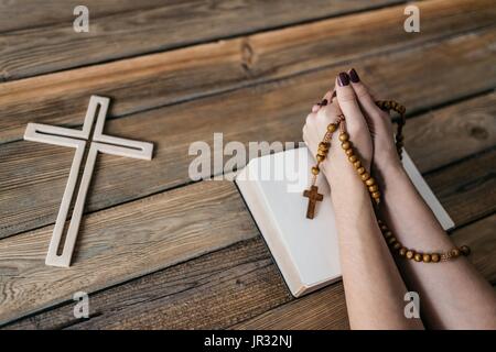 Jeune femme priant mains avec du chapelet et la Sainte Bible. Concept de la Religion Banque D'Images