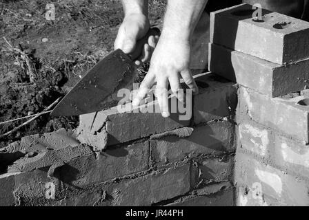 Gros plan du charpentier construction d'une maison extension. Photo montre homme tenant une truelle tout en jetant des briques. Banque D'Images