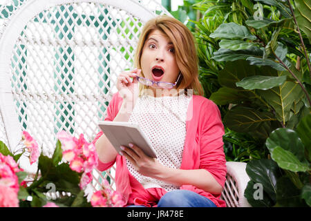 Belle surprise woman with tablet parmi les fleurs Banque D'Images