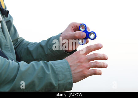 L'homme à l'aide de spinner l'extérieur. La main de l'homme à s'agiter sur fond blanc. Banque D'Images