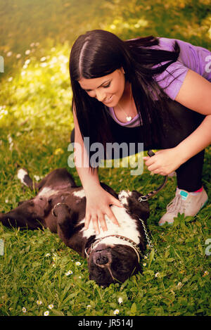 Belle Jeune femme jouant avec son joli stafford terrier dans le parc. Banque D'Images