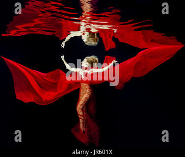 Femme dans une robe rouge dans la piscine Banque D'Images