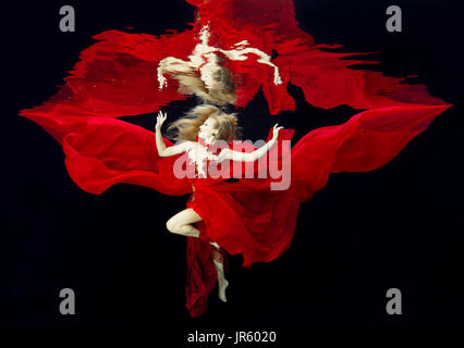 Femme dans une robe rouge dans la piscine Banque D'Images