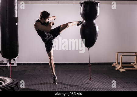Boxeur avec sac en action - un homme avec un tatouage en rouge des gants de boxe - Boxe sur fond noir - le concept d'un mode de vie sain - l'idée Banque D'Images